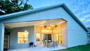 A modern house with a covered patio, large windows, and a dining area. - The Sanford Ave House with fully-fenced yard (Sanford)
