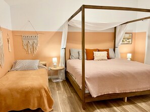 Cozy retreat with a four-poster bed and two additional beds, complete with bedside tables and lamps.