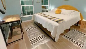 A bedroom with a bed, a desk, and two rugs. - The Sanford Ave House with fully-fenced yard (Sanford)
