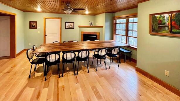 A dining area with a wooden table and chairs, a fireplace, and a large window.