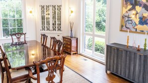 A dining room with a glass-top table, wooden chairs, a cabinet, and large windows. - Welcome to Summerville! 1.0 miles from the Augusta National (Augusta)