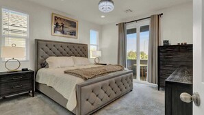 A bedroom with a tufted headboard bed, a nightstand, a dresser, and a chandelier.