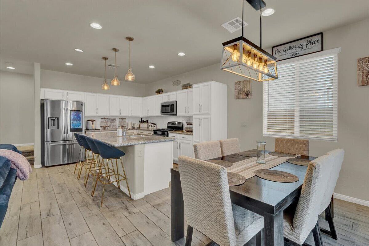 A modern kitchen with white cabinets, stainless steel appliances, and a central island with bar stools.