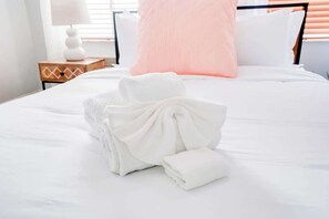 A neatly made bed with a folded towel and a decorative pillow.