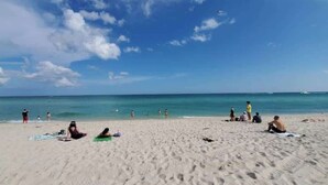 A beach with people sunbathing and swimming. - Comfy Studio with Beach Access across the street (Miami)