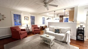 A living room with a white sofa, two red armchairs, a glass coffee table, and a ceiling fan. - Historical charm | Modern amenities | Unbeatable location (Ogunquit)