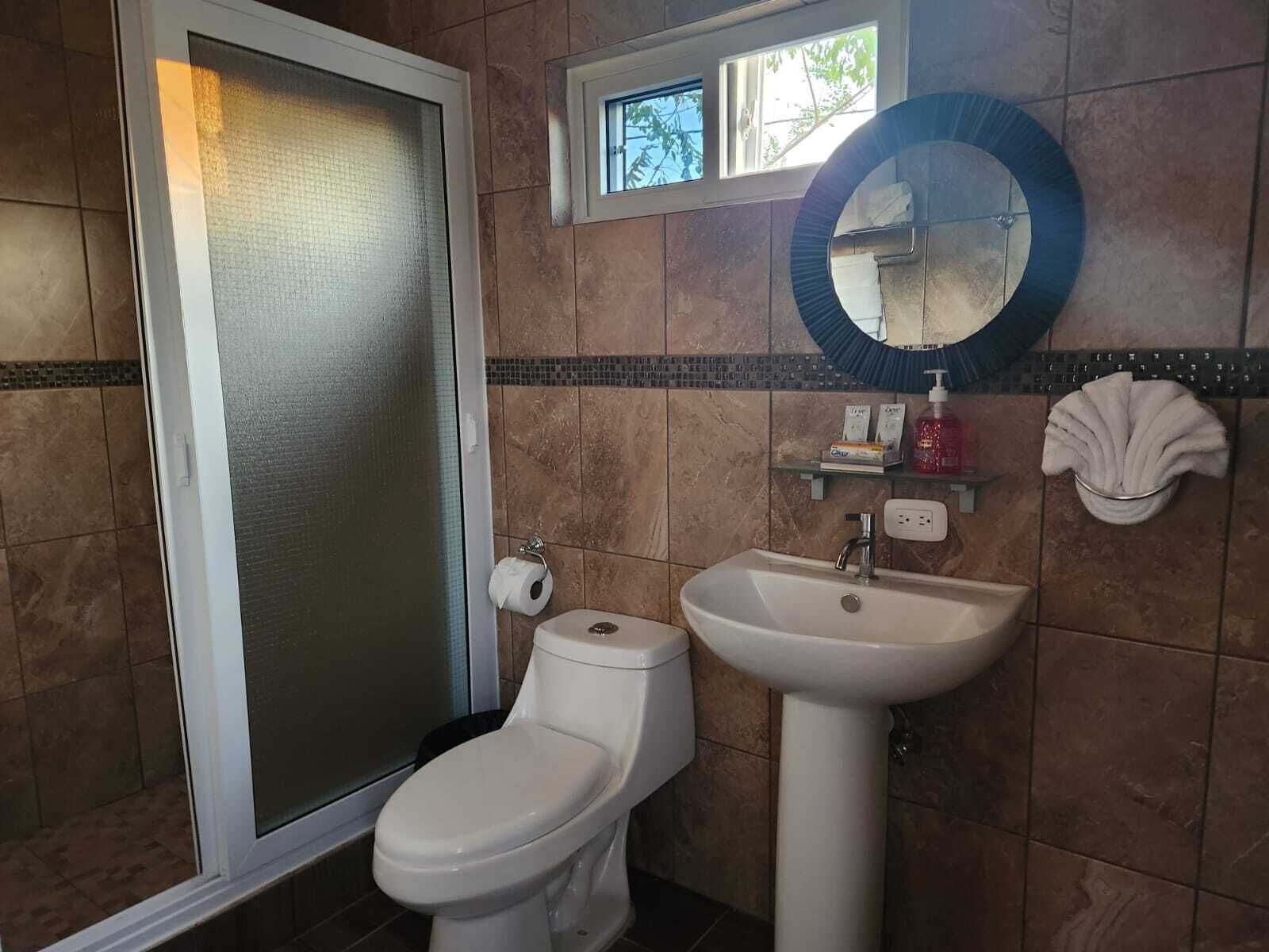 A bathroom with a toilet, sink, and a window above the sink.