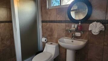 A bathroom with a toilet, sink, and a window above the sink.