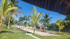 A pathway leading to a building with a red roof, surrounded by palm trees and a clear blue sky. - VILLA CLAUDIAS (Taxisco)