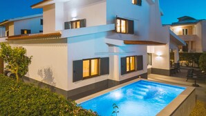 A modern two-story house with a swimming pool, multiple windows, and a balcony. - Portimão: villa with heatable pool & BBQ (Portimão)