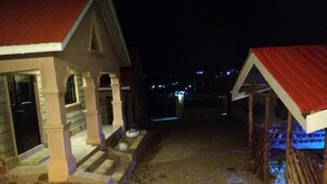 Un bâtiment avec un toit rouge et des murs en pierre, un chemin de gravier et une clôture en bois.