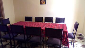 A dining area with a red checkered tablecloth, six black chairs, and a framed picture on the wall.