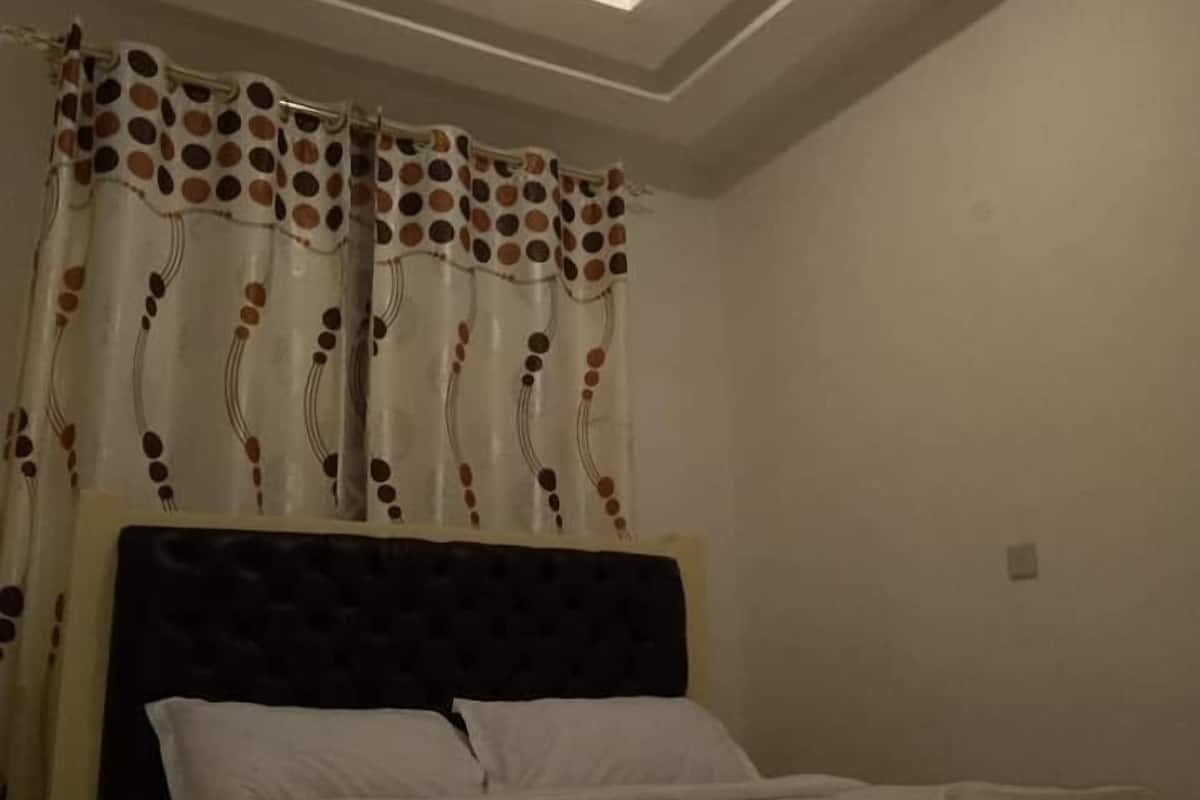 A bedroom with a bed, a skylight, and a curtain with a polka dot pattern.