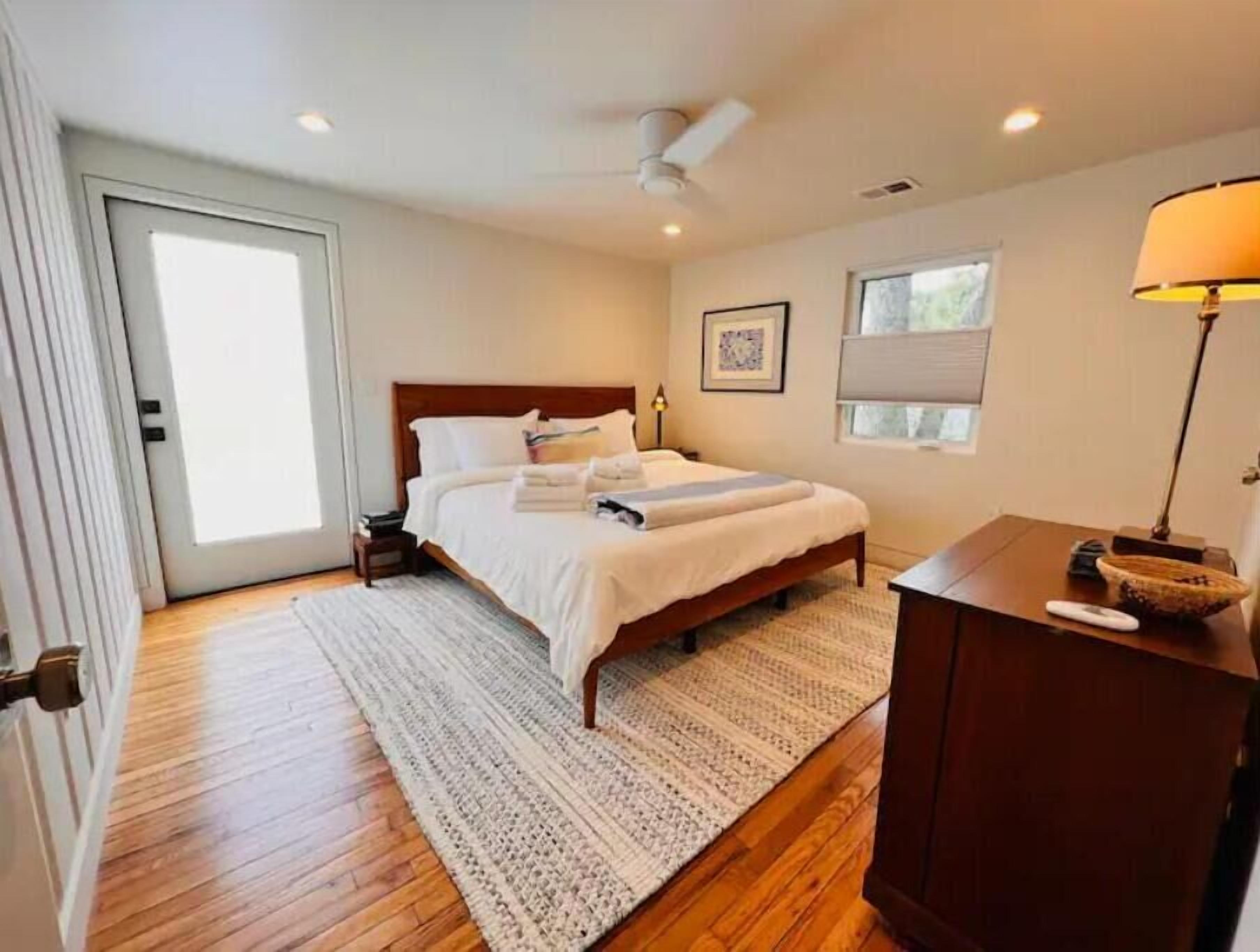 A bedroom with a bed, a desk, a lamp, and a window.