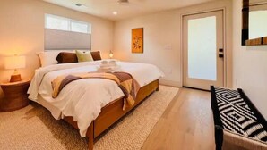 Een moderne slaapkamer met een groot bed, nachtkastjes, een plafondventilator en uitzicht op buiten.