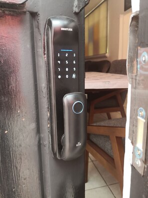 A black electronic keypad lock with a numeric keypad and a rotary dial, attached to a metal door frame.