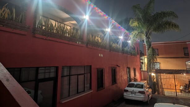 Un bâtiment rouge avec de nombreuses fenêtres et une voiture blanche garée devant.