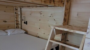 A bunk bed with a wooden headboard, a white mattress, and a white pillow. A wooden ladder is attached to the bed frame. - Cozy lodge room #2 (Mars Hill)
