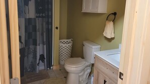 A small bathroom with a toilet, a white cabinet above the sink, and a towel hanging on a hook. - Cozy lodge room #2 (Mars Hill)
