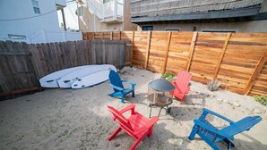 En have med træhegn, surfbræt og flere Adirondack-stole.