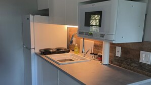 Een moderne keuken met witte kasten, een roestvrijstalen spoelbak en een ingebouwde kookplaat, met een raam boven de spoelbak.