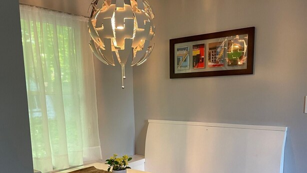Een moderne keuken met een wit aanrecht, een hanglamp en een lijst met een afbeelding aan de muur.