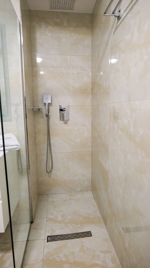 Chuveiro sem barreiras com porta de vidro, chuveiro manual e painel de controle na parede.