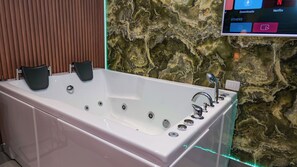 A modern bathroom with a large bathtub, a wooden panel wall, and a decorative stone wall. - Villa313 (Tirana)