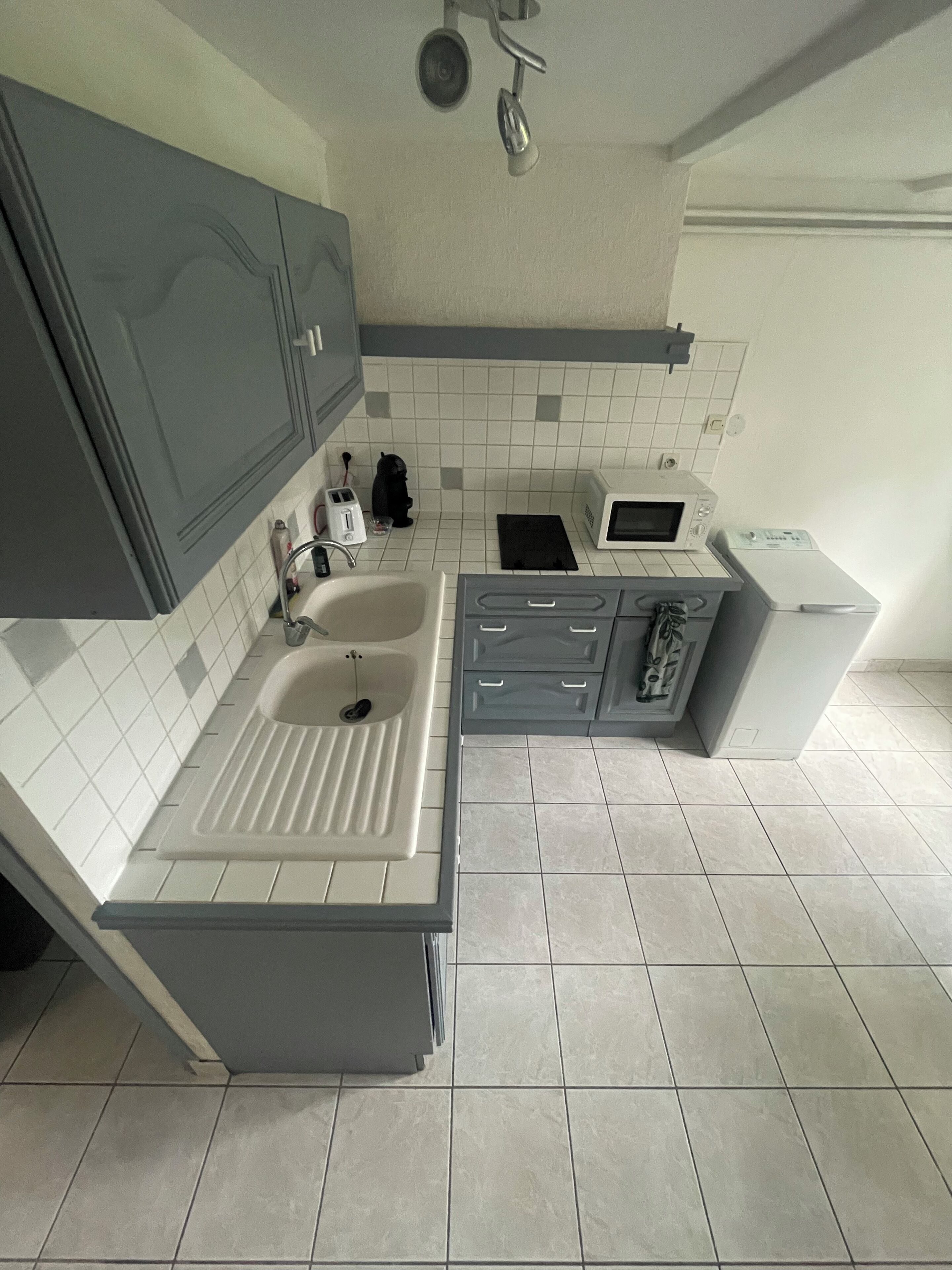 A modern kitchen with grey cabinets, a white sink, a microwave, and a built-in oven.