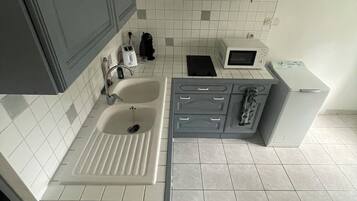 A modern kitchen with grey cabinets, a white sink, a microwave, and a built-in oven.