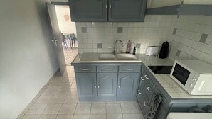 A kitchen with grey cabinets, a white sink, and a microwave. - Apparemment à Côté du Meet (Cornebarrieu)