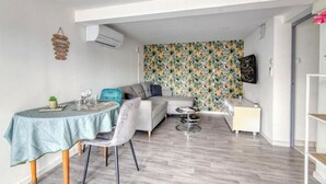 A modern living room with a dining area, a grey sofa, a patterned wallpaper, and a small table with chairs. - Apparemment à Côté du Meet (Cornebarrieu)