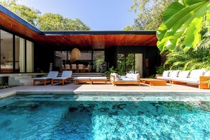 A modern outdoor pool area with lounge chairs and a wooden deck. - Luxury 4-Bedroom Getaway be surrounded by Nature, K Section Nosara (Nosara)