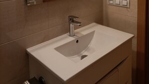 A modern bathroom with a white sink, a mirror, and three pendant lights. - Funcional Apartamento en Iturrama (Pamplona)