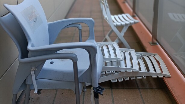 A balcony with two white plastic chairs and a white table, a tiled floor, and a metal railing. - Funcional Apartamento en Iturrama (Pamplona)