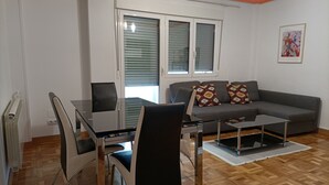 A modern living room with a grey sofa, patterned cushions, a glass dining table, and black chairs. - Funcional Apartamento en Iturrama (Pamplona)