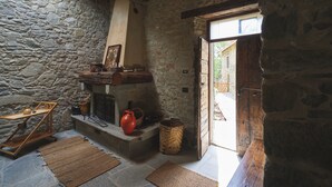 A rustic stone-walled room with a fireplace, wooden furniture, and a basket. - "Historic Sillico Relais - Hot Tub, Sauna&Charme" (Sillico)