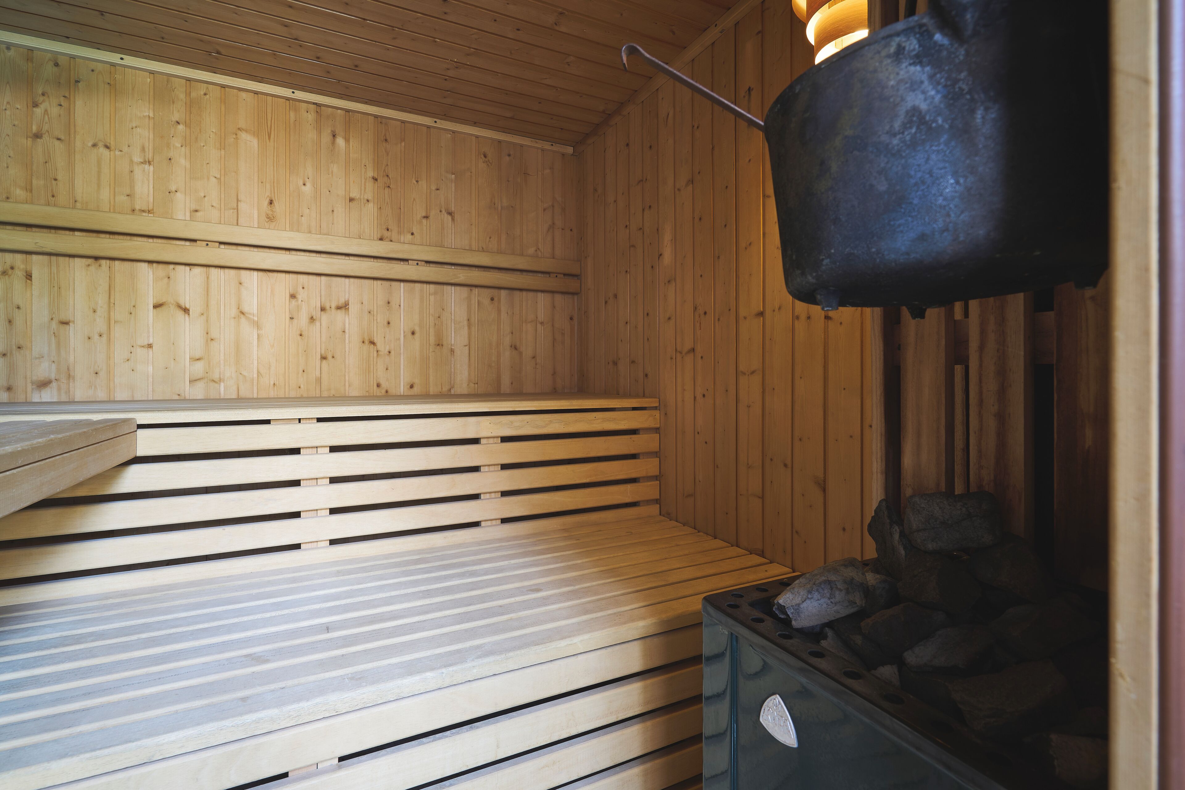 A sauna with wooden benches and a stone heating element.