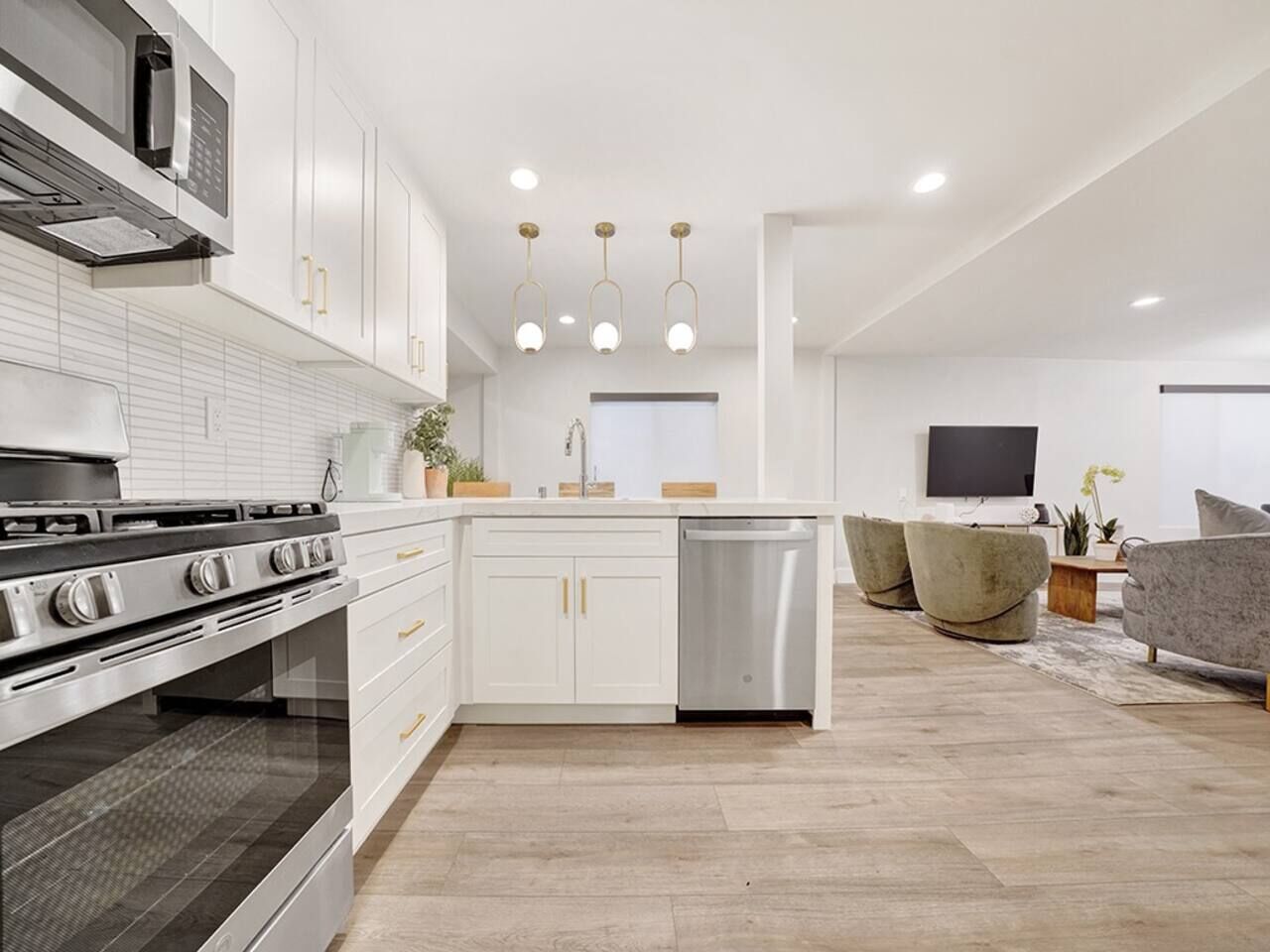 Una cocina moderna con gabinetes blancos, electrodomésticos de acero inoxidable y una isla central.