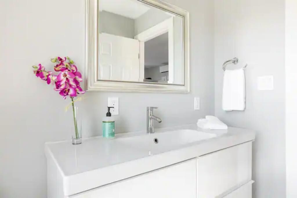 Un meuble-lavabo blanc pour la salle de bain, avec un miroir, un évier et une serviette accrochée au mur.