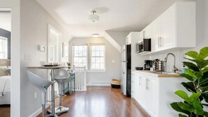 Une cuisine moderne avec des armoires blanches, des appareils en acier inoxydable et un coin bar équipé de tabourets.