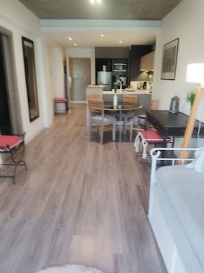 Una sala de estar moderna con comedor, piso de madera y un sofá.