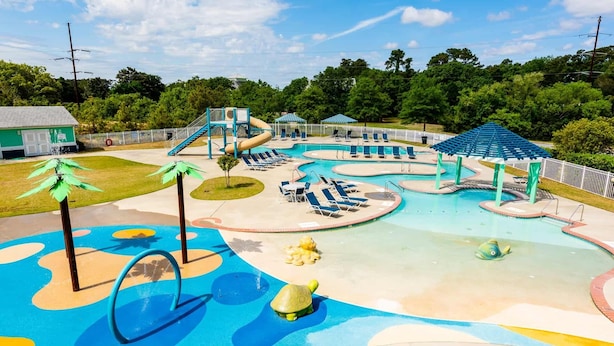 Um parque aquático com várias piscinas, toboáguas e espreguiçadeiras.