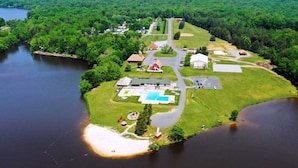 An aerial view of a lakeside property with a swimming pool, a red barn, and a large house. - Wilderness Presidential Resort Cabins (Spotsylvania)