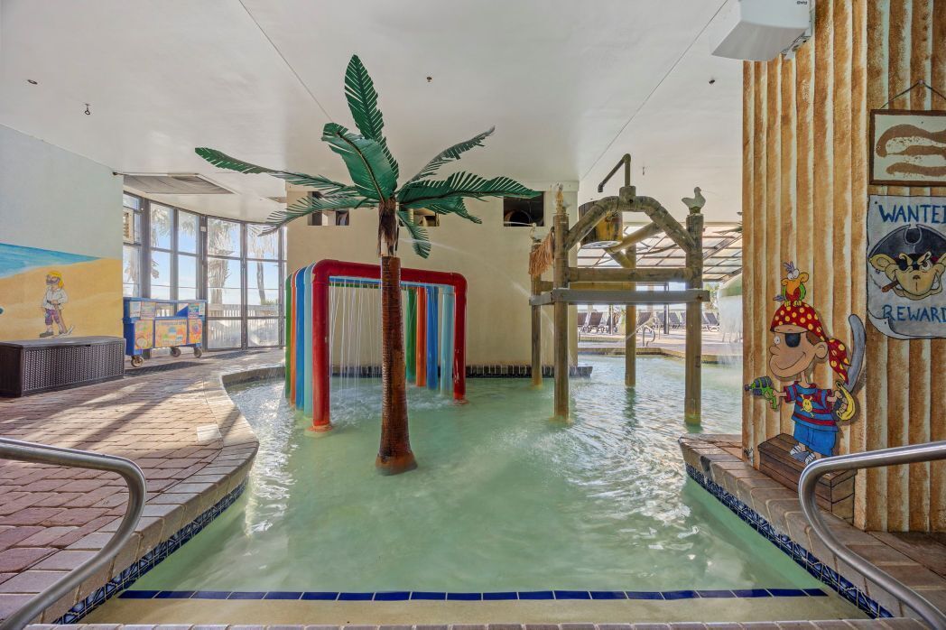 An indoor water park with a palm tree, colorful slides, and a 'WANTED' sign.
