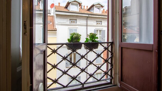 A balcony with a metal railing and two flower planters. - Dockside Studio (Milano)