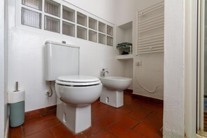 A bathroom with a toilet, bidet, and a shelf above the toilet. - Dockside Studio (Milano)