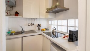 A modern kitchen with white cabinets, a stainless steel sink, a kettle, and a coffee machine. - Dockside Studio (Milano)