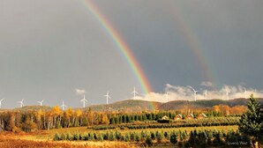 Eine Landschaft mit Windkraftanlagen und einem Regenbogen.
