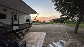 A recreational vehicle parked in a grassy area with a picnic table and chairs.